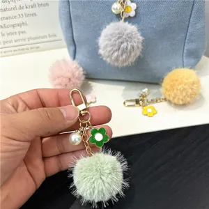 Macro detail view of colorful flower pom-pom keychain with pearl charm and golden clip