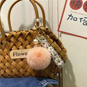 Macro view of creative floral ribbon and pink plush pom-pom keychain with white pearl