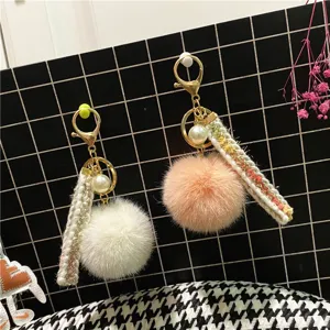 Close-up detail showing the texture of tweed style pom-pom keychain with pearl and ribbon.