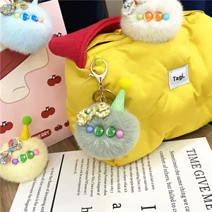 Detailed view of a cute fuzzy plush ball keychain with a mini cone hat on a yellow bag