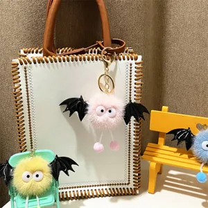 Detail shot of cute colorful plush bat monster keychains hanging on bag and props