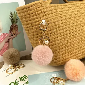 Detailed view of soft plush pompom keychain with pearl charm on a stylish straw bag
