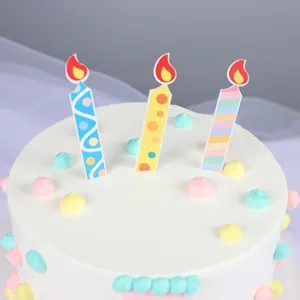 Primo piano di tre topper per torte a forma di candela su una torta bianca cremosa