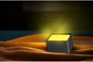Detail view of a modern creative night light and digital clock, glowing with warm yellow light.