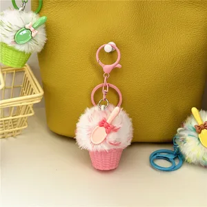 Close-up of a cute pink plush ice cream keychain charm hanging on a yellow textured bag.
