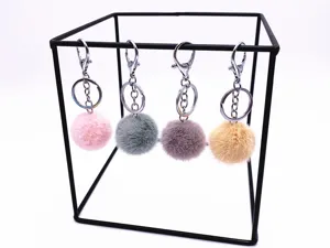 Detail view of four colorful plush pom-pom keychains hanging on a display stand
