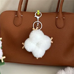 Close-up of white plush tofu-shaped bag charm with wooden sticks on brown leather bag