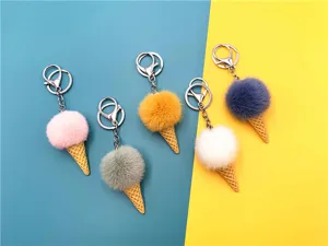 Colorful faux fur ice cream cone pom-pom keychains on a split teal and yellow background.