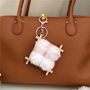Creative fermented bean curd plush keychain charm hanging on a brown leather handbag