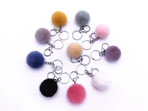 Assorted colorful plush fur ball keychains arranged in a circle on white background