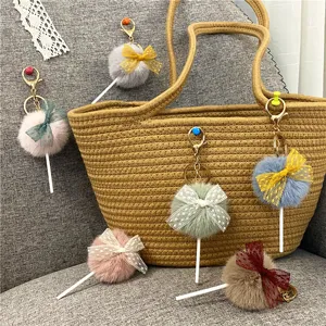 Detailed view of colorful plush lollipop bag charms with lace bows on a woven bag.