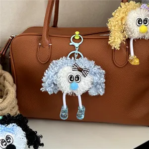 Detailed view of a cute blue curly plush doll keychain hanging on a brown leather bag.