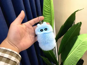 Detail view of a cute light blue fluffy caterpillar plush keychain with sunglasses.
