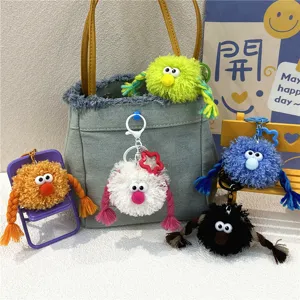 Detailed view of colorful plush monster keychains with braided hair as bag charms.