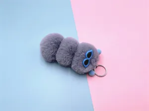 Close-up view of a cute purple plush caterpillar keychain with blue sunglasses charm.