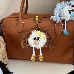 Close-up macro detail of cute frizzy hair doll keychain hanging on brown leather bag