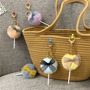 Detailed shot showing multiple colorful plush lollipop keychains with lace bows on a bag