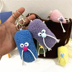 Macro view of several colorful fuzzy plush character keychains with googly eyes