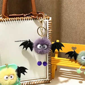 Detailed view of cute plush monster keychain with black bat wings and large eyes.