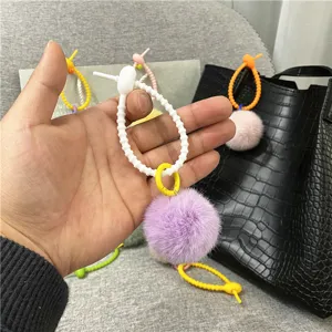 Detailed macro view of a purple plush pom pom bag charm with a white silicone ring