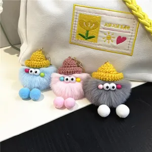Close-up of cute fuzzy coal ball plush keychains in three colors used as bag charms