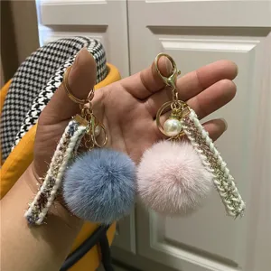 Detailed view showing the soft texture of plush pom pom keychains with tweed ribbon