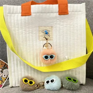 Cute fuzzy pom-pom keychains with sunglasses and pearl charm on quilted bag