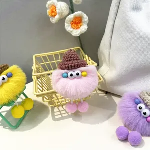 Detailed close-up of fuzzy monster keychains in pink, yellow, and purple colors.