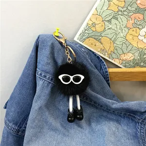 Close-up of a cute black fluffy monster keychain with white sunglasses and shoes