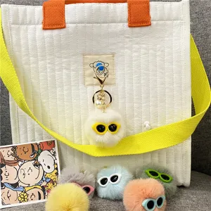 Close-up detail of colorful fluffy monster ball keychains with cute glasses and pearl charms