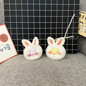 Macro view of two cute white plush rabbit head keychains with colorful hair clips.