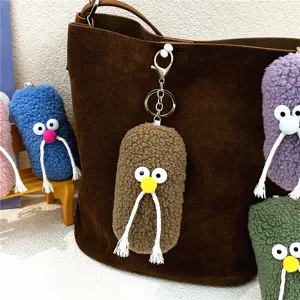 Macro view of colorful plush mustache keychains as cute charms on a brown leather bag.