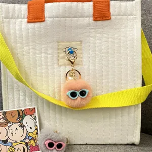 Detail shot of a cute peach plush monster keychain with sunglasses and pearl charm.