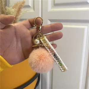 Close-up of elegant pink pom-pom keychain with gold hardware and pearl charm detail
