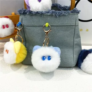 Close-up of cute plush cat head keychains hanging on a denim bag as accessories