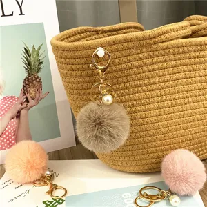 Close-up detail of a soft fluffy faux fur pom-pom keychain with elegant pearl charm.
