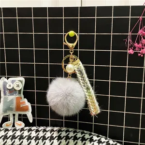 Close-up of elegant grey faux fur pom-pom keychain with pearl and tweed ribbon detail