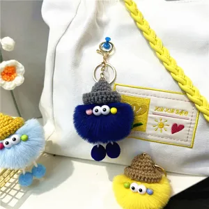 Cute fuzzy monster doll keychains in various colors attached to a white canvas bag