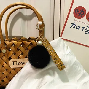 Close-up of floral ribbon keychain with black plush pompom and pearl charm