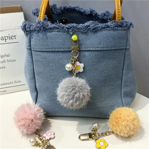 Detailed view of colorful pom-pom charms featuring flower and pearl accents for bags.