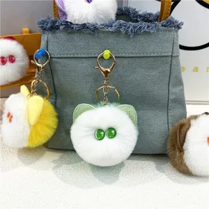 Detailed close-up of several cute plush cat head keychains attached to a denim bag charm