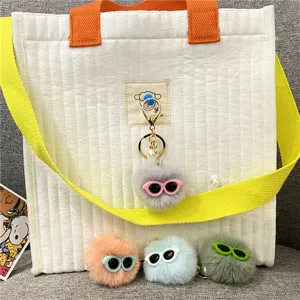 Detailed view of colorful plush pom-pom monster keychains with miniature sunglasses
