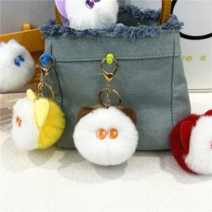 Close-up of plush cat head keychains hanging on a denim bag as cute decorative accessories.