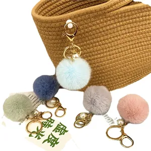 Cute macaron-colored fur ball keychains with pearl accents and gold rings for bags