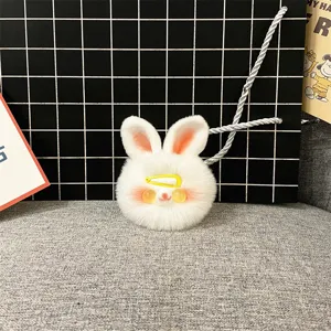 Detail view of a cute white fluffy rabbit plush keychain with a tiny yellow hairclip