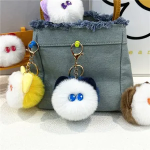 Detailed view of colorful plush cat head keychains with cute eyes on a denim bag