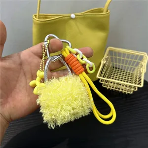 Close-up detail of a cute yellow plush bag charm featuring a silver heart carabiner
