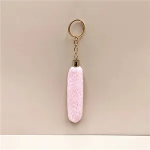 Detailed macro shot of a fluffy pink plush keychain with a shiny gold-tone metal ring.
