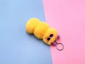 Detailed view of a cute fuzzy yellow caterpillar plush keychain charm with cartoon eyes