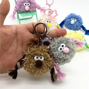 Detail view of a quirky plush monster keychain with braided hair and funny eyes.